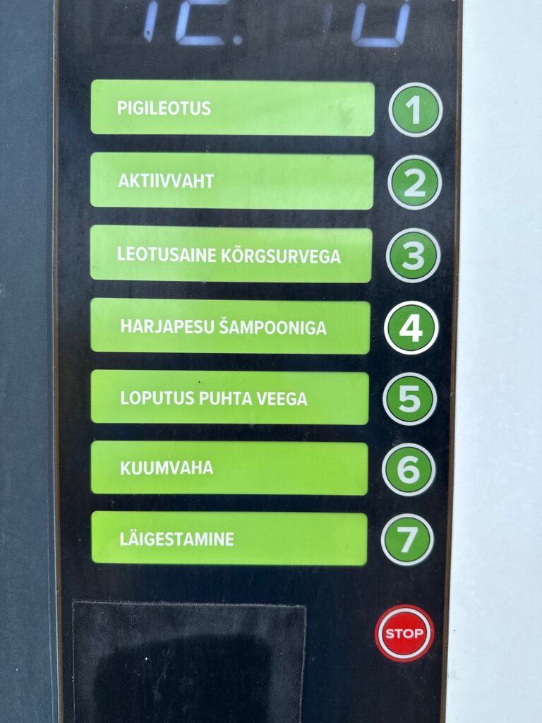 Baltikum 2025 – Lettland 2 – 17 Nahaufnahme eines Bedienfelds mit sieben grünen Tasten mit estnischer Beschriftung und den Nummern 1 bis 7 für verschiedene Autowaschoptionen sowie einer roten „STOP“-Taste unten.